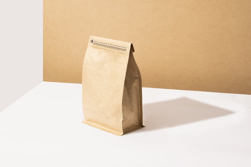 A kraft paper bag of coffee beans on a pale surface