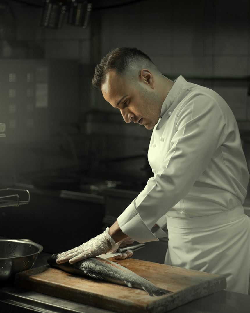 Head chef preparing fish at the pass