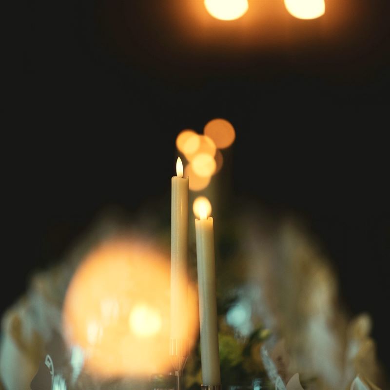 Tapered candles burning on a table at the back of the room