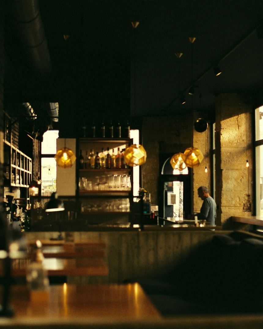 The dining room at dusk, lit by pendant lamps over dark timber
