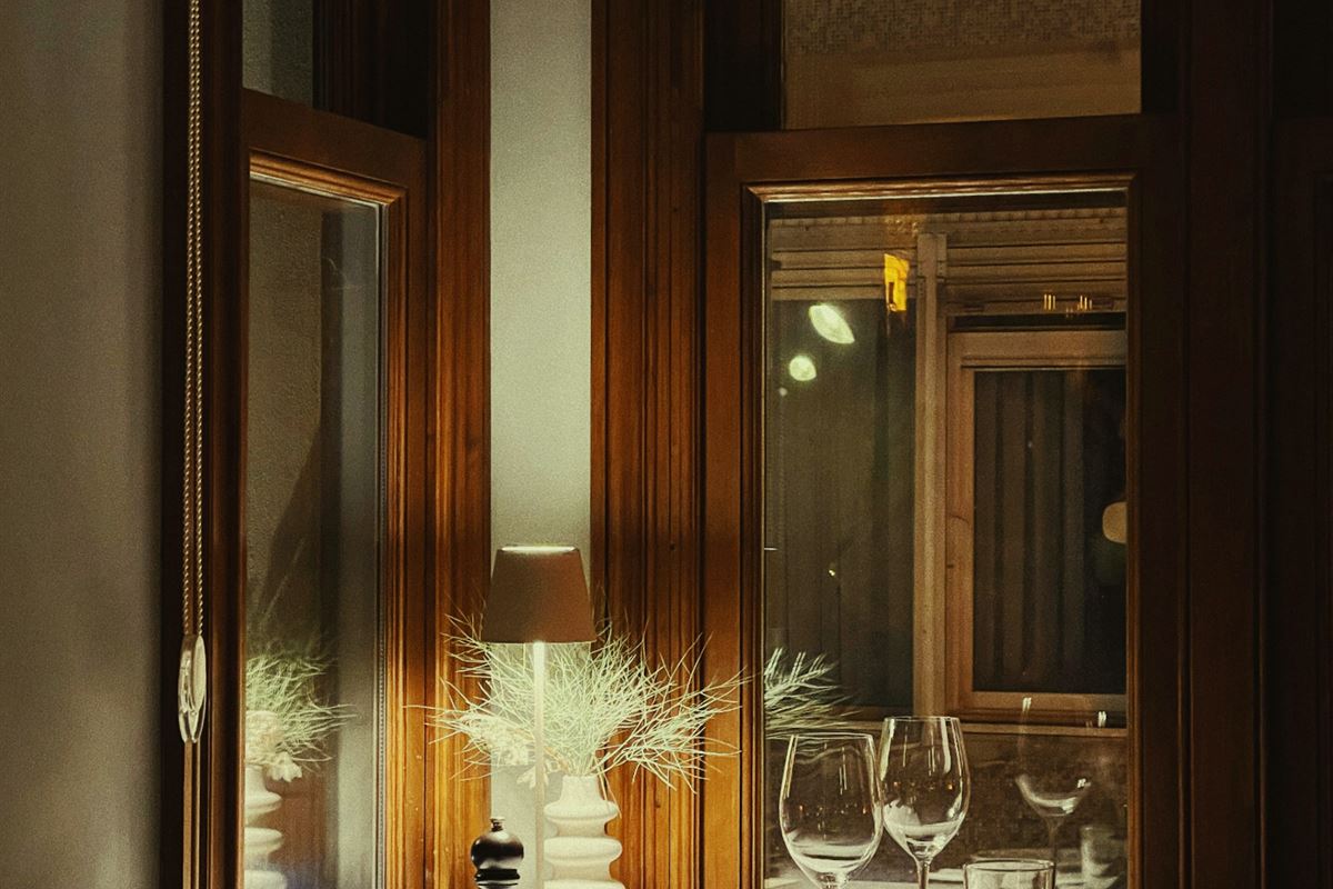 A dining table laid with wine glasses and candles before service