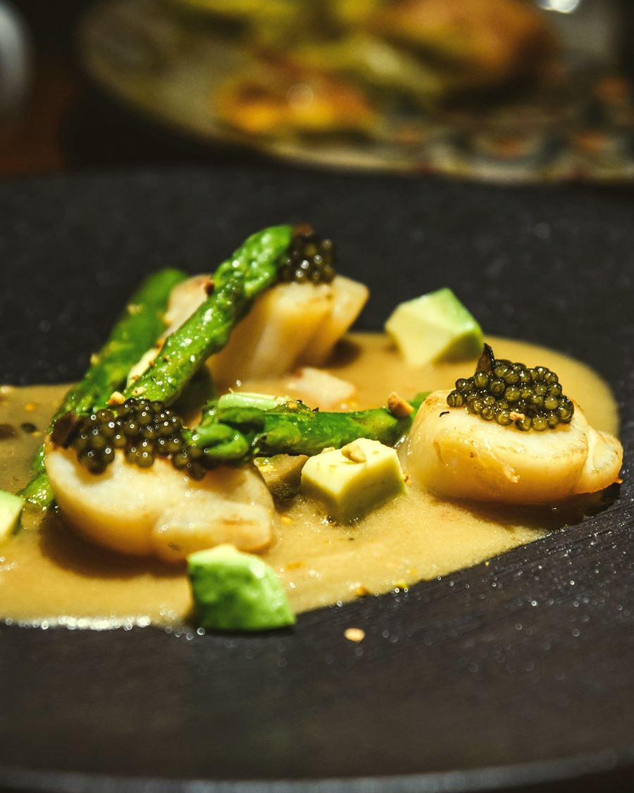 Hand-dived scallops with caviar and asparagus, plated on dark slate