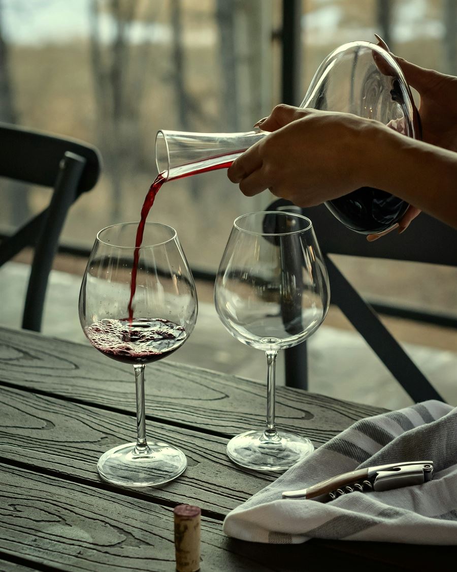 Red wine poured from a decanter into two glasses